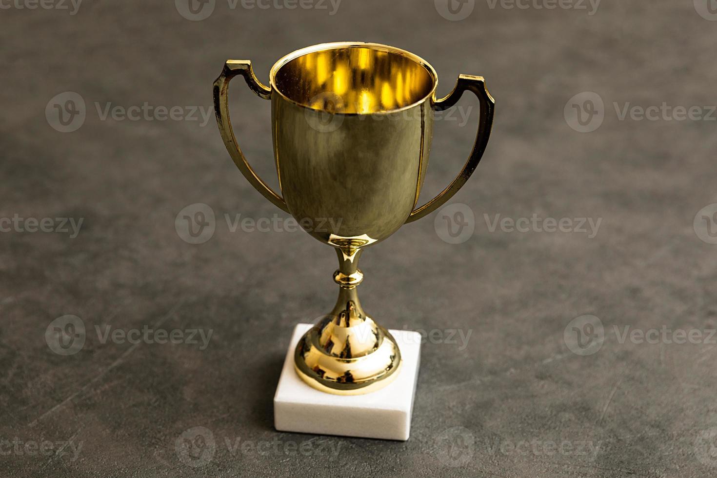 Simply design winner or champion gold trophy cup on concrete stone grey background. Victory first place of competition. Winning or success concept. Top view copy space. photo