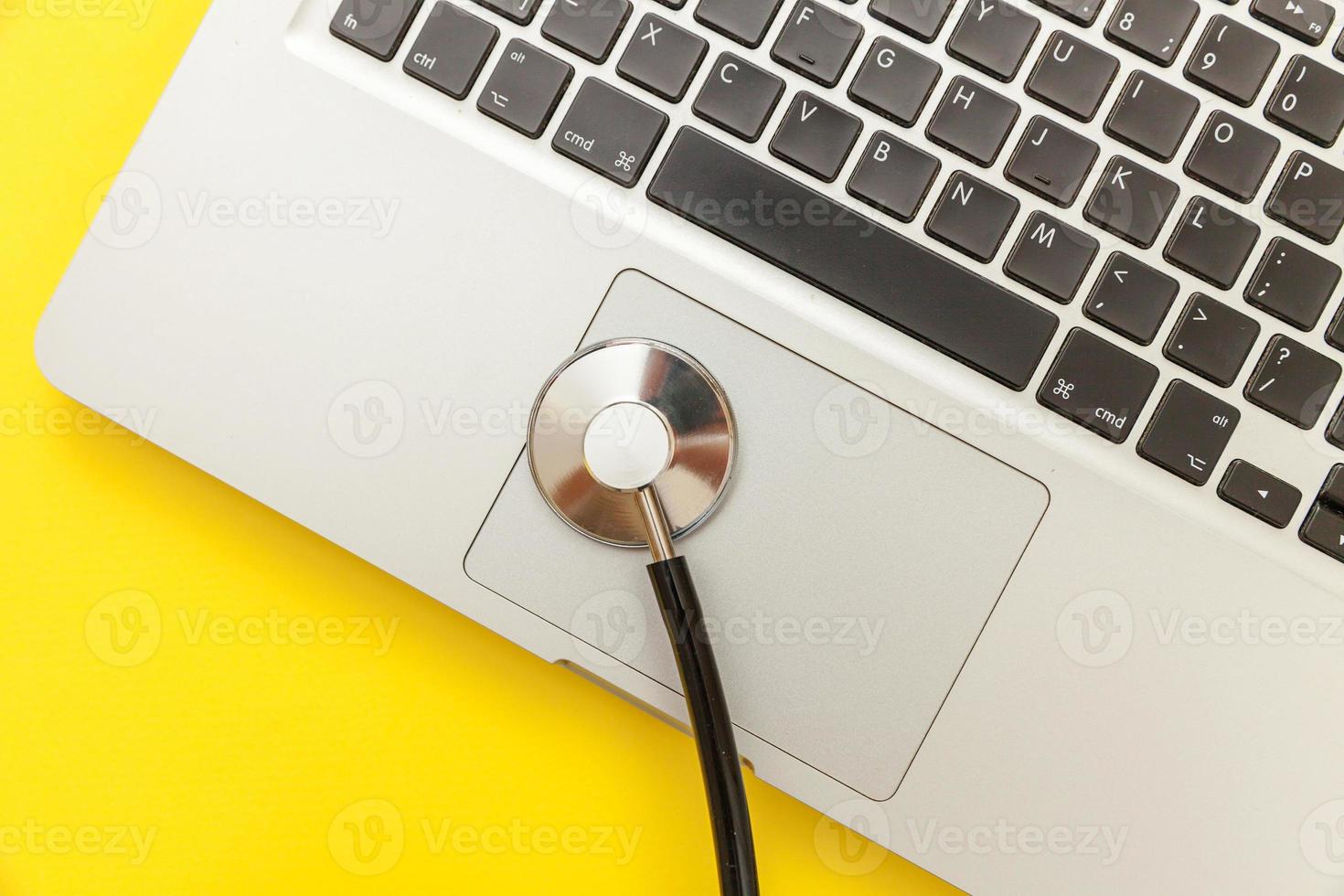 Stethoscope keyboard laptop computer isolated on yellow background. Modern medical Information technology and sofware advances concept. Computer and gadget diagnostics and repair photo