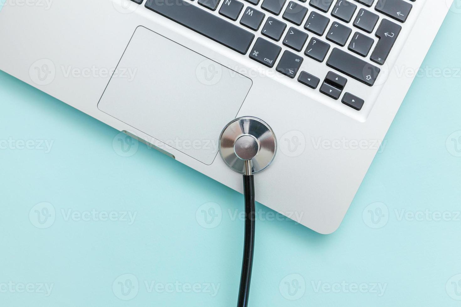 Stethoscope keyboard laptop computer isolated on blue background. Modern medical Information technology and sofware advances concept. Computer and gadget diagnostics and repair photo