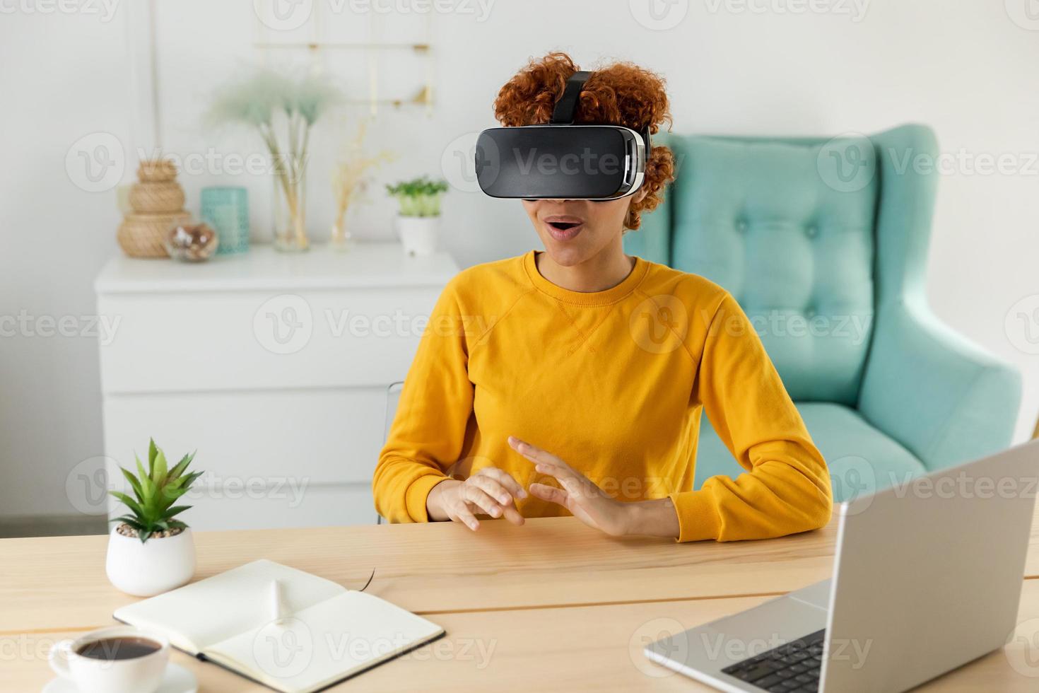African american young woman wearing using virtual reality metaverse VR glasses headset at home. Girl on virtual reality helmet. Technology simulation hi-tech videogame concept. photo