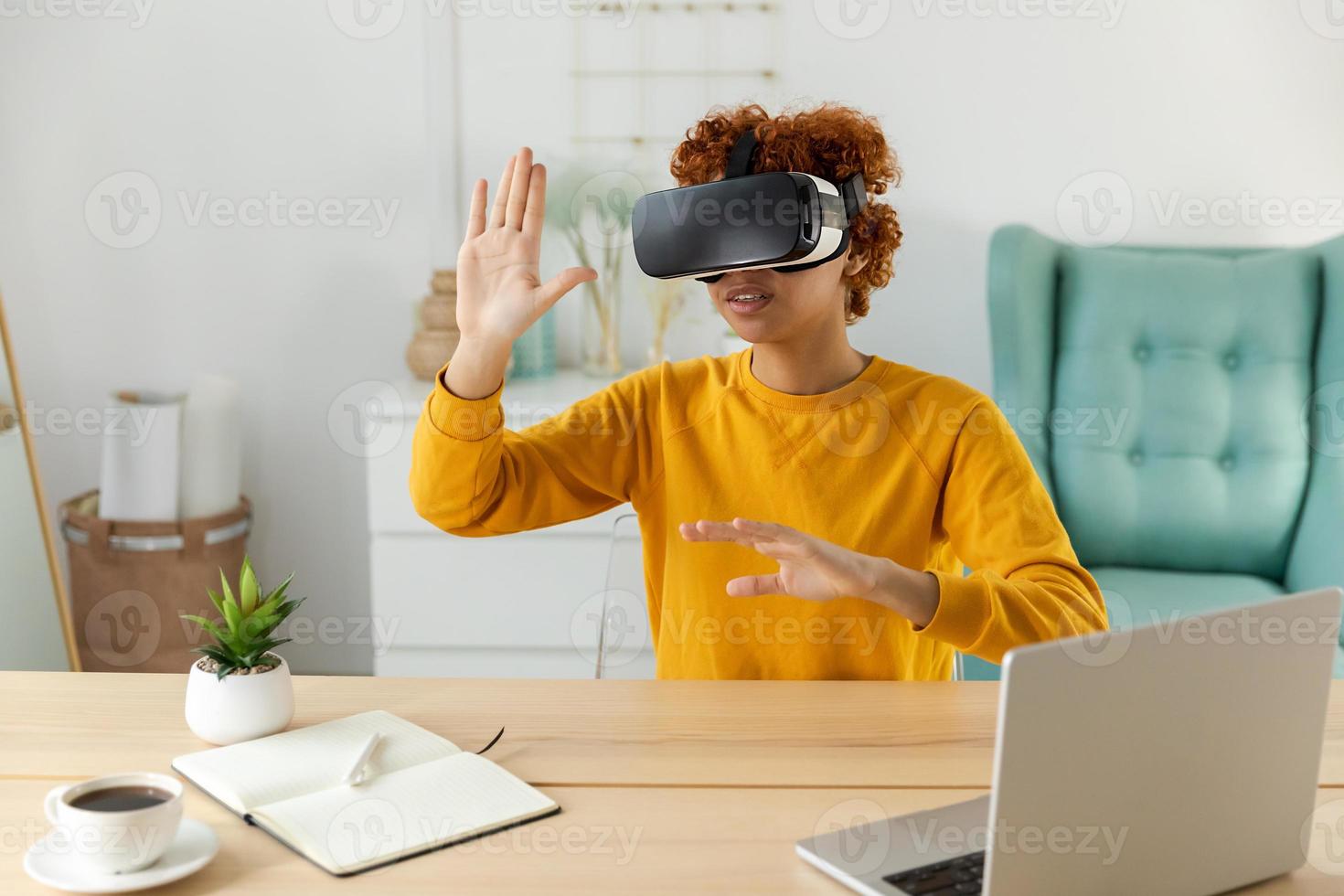 African american young woman wearing using virtual reality metaverse VR glasses headset at home. Girl touching air during VR experience on virtual reality helmet. Simulation hi-tech videogame concept. photo