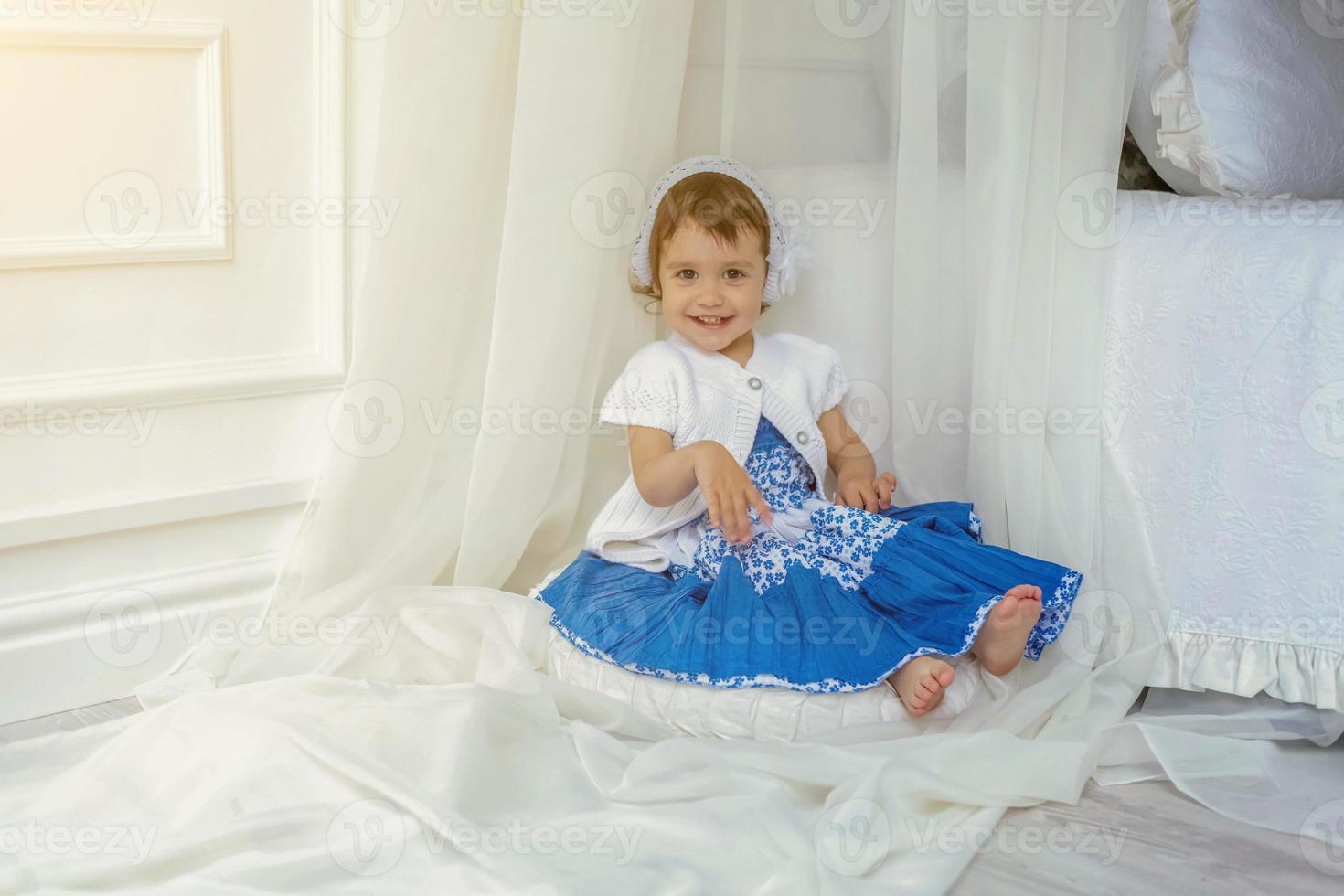 Cute little girl playing in light white bedroom photo