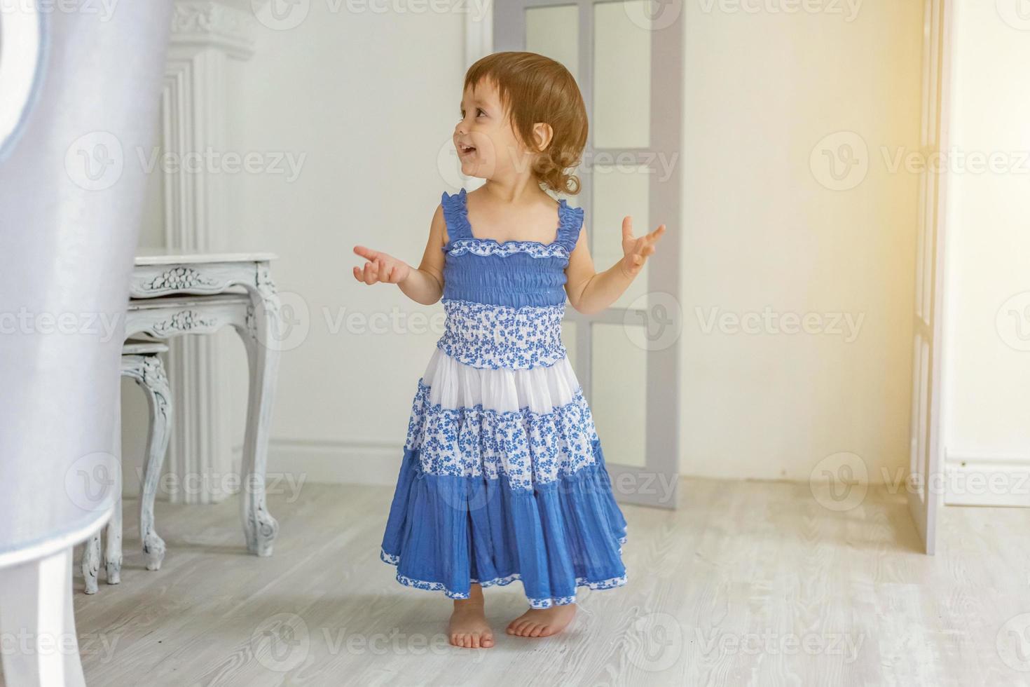 Little girl dancing in bright light living room at home and laughing photo