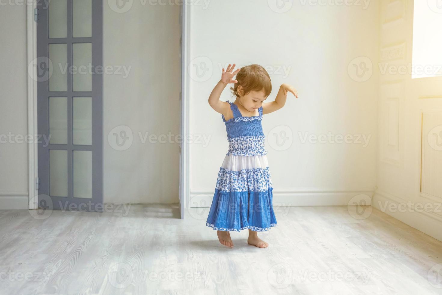 Little girl dancing in bright light living room at home and laughing photo