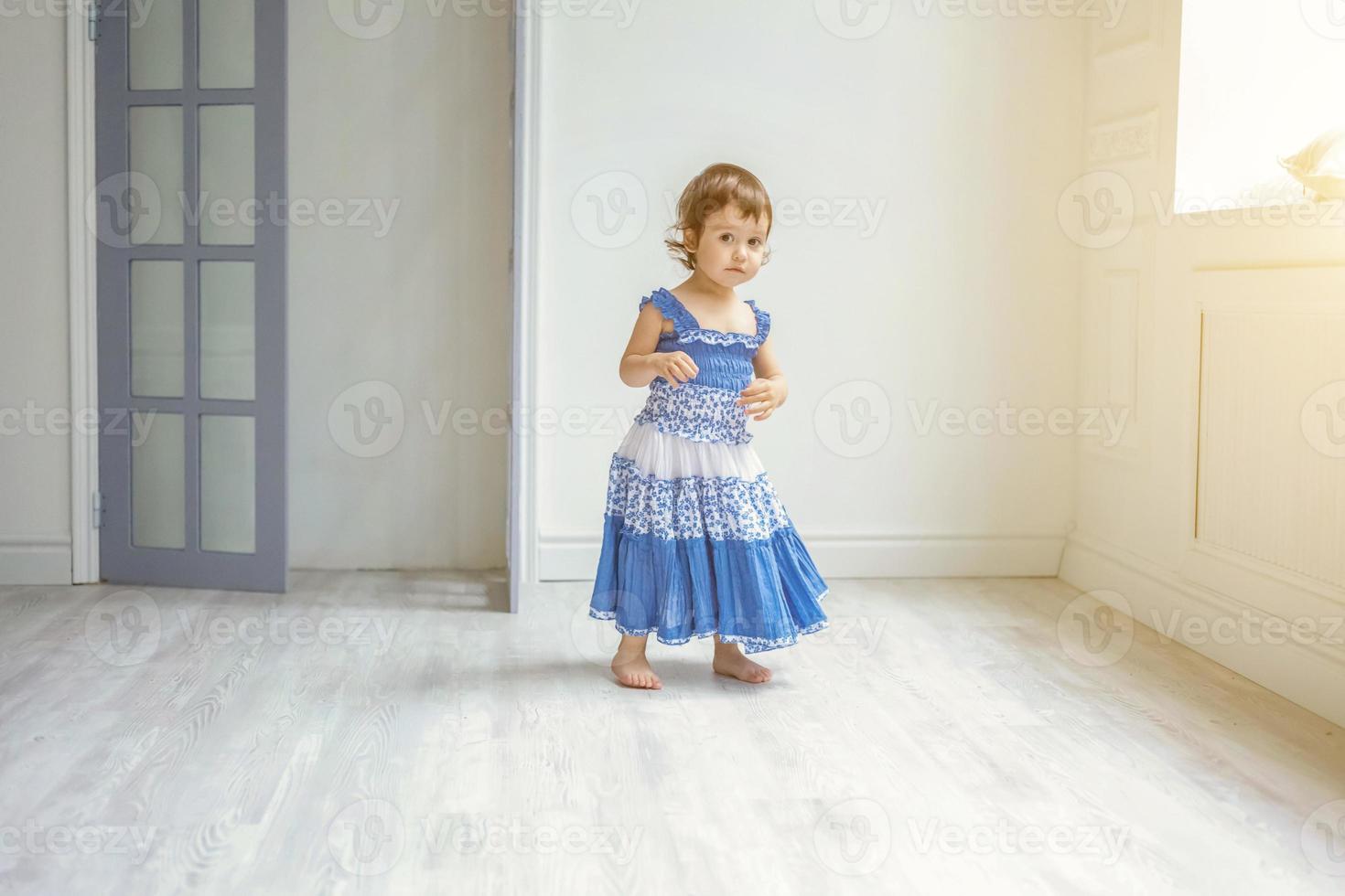 Little girl dancing in bright light living room at home and laughing photo