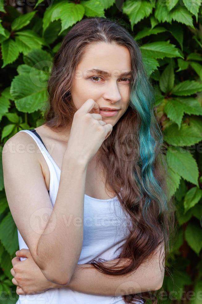 hermosa joven hipster brunete niña con largo verde pelo sonriente en parque antecedentes foto