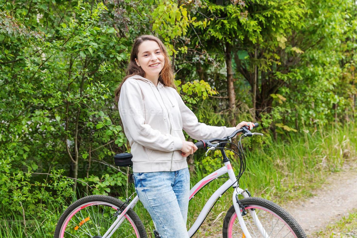 Young woman riding bicycle in summer city park outdoors. Active people. Hipster girl relax and rider bike photo