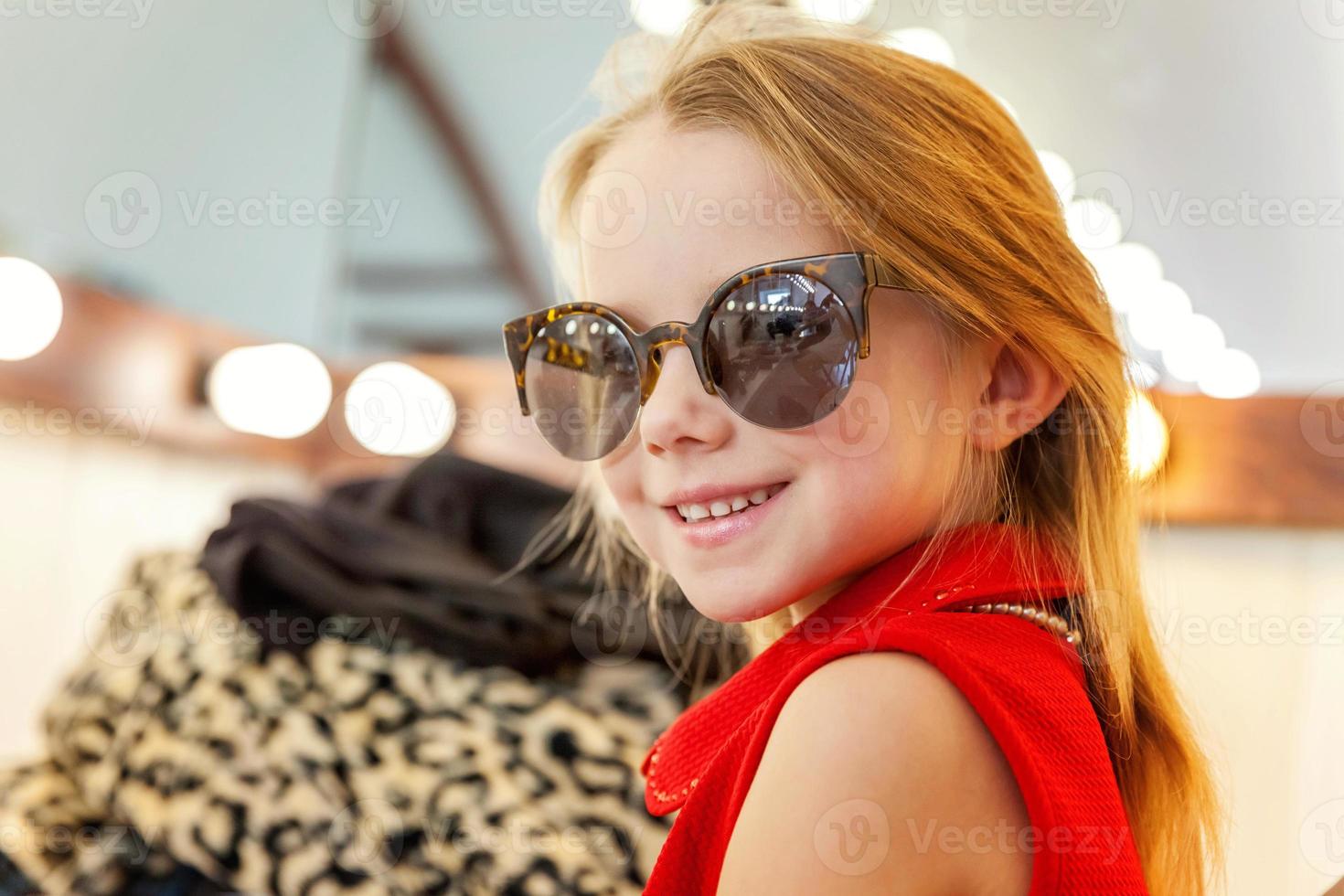 Little girl in sunglasses near mirror photo