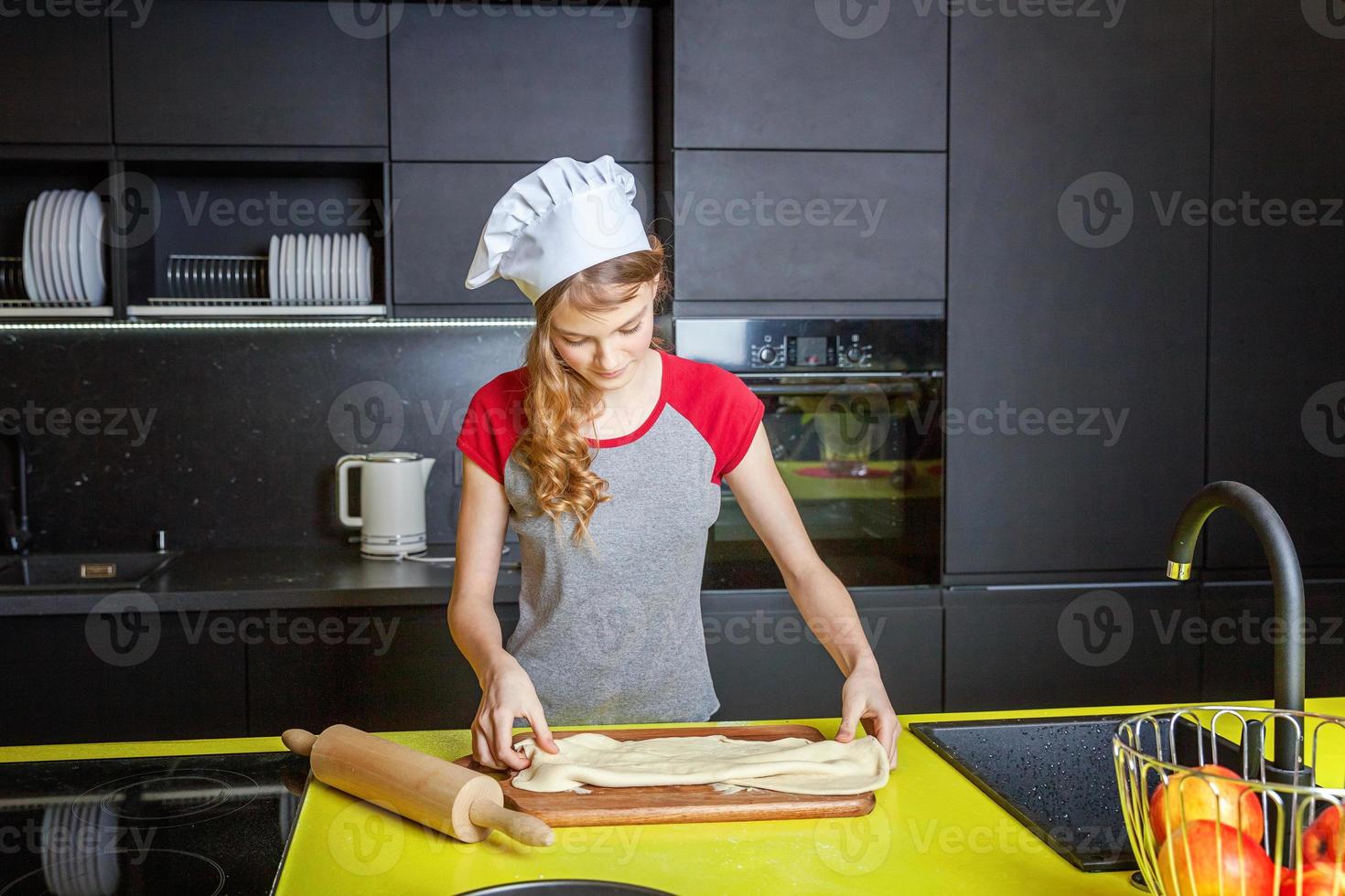 Teenage girl preparing dough, bake homemade holiday apple pie in kitchen photo