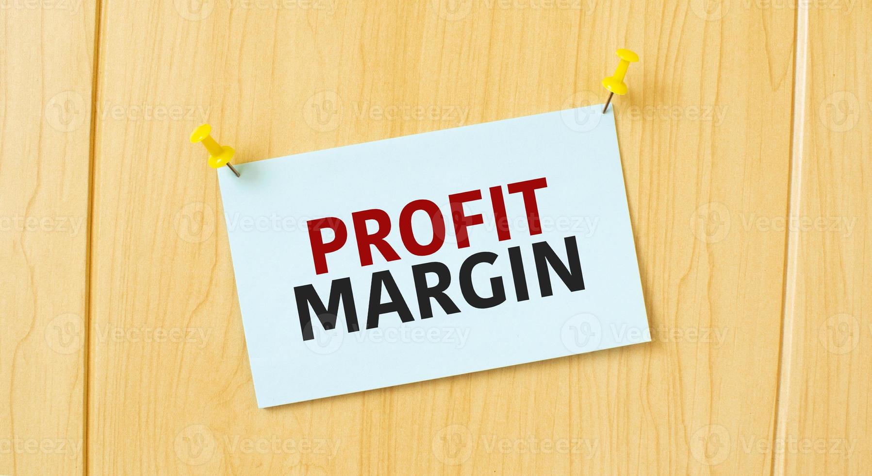 profit margin sign written on sticky note pinned on wooden wall photo