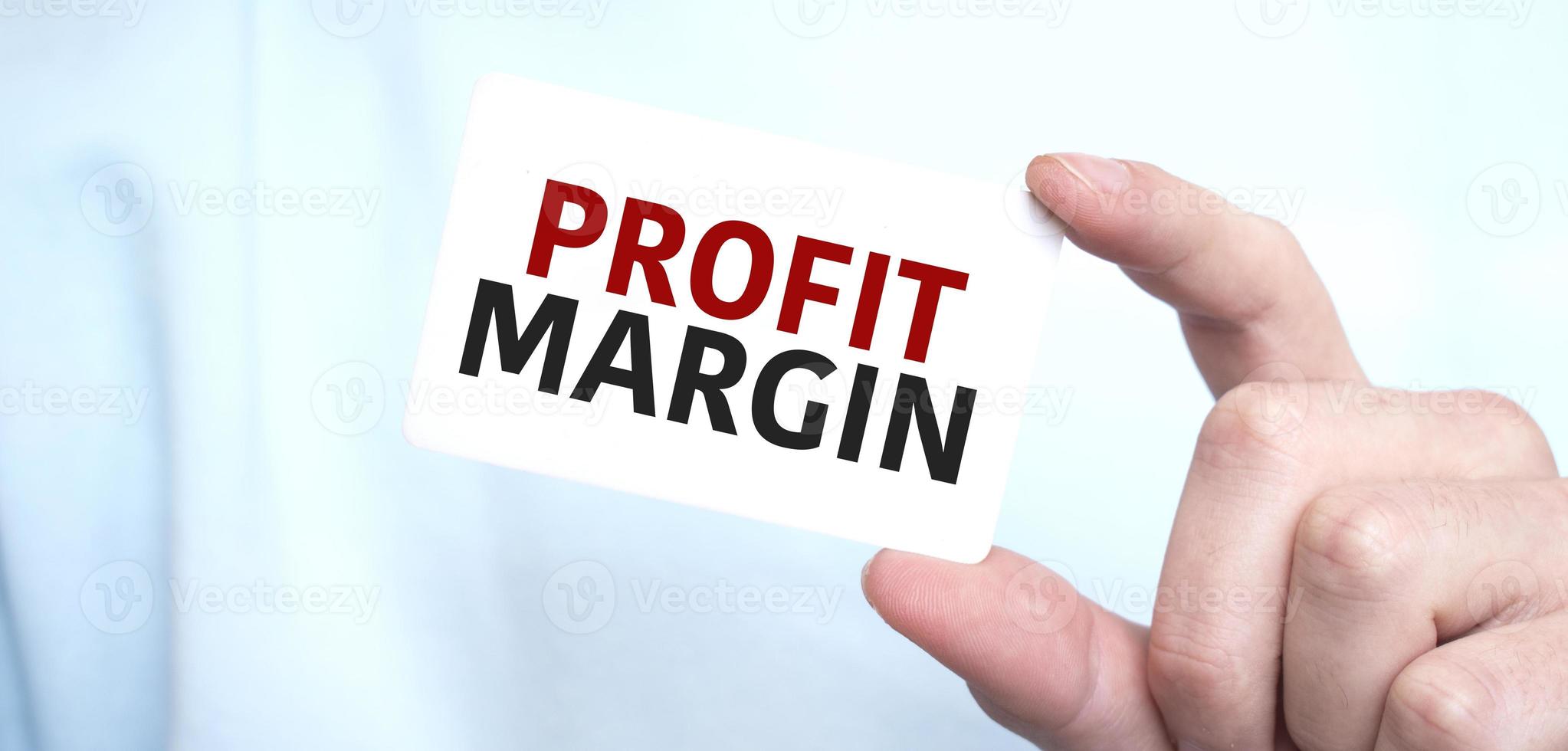 Man in blue sweatshirt holding a card with text profit margin ,business concept photo