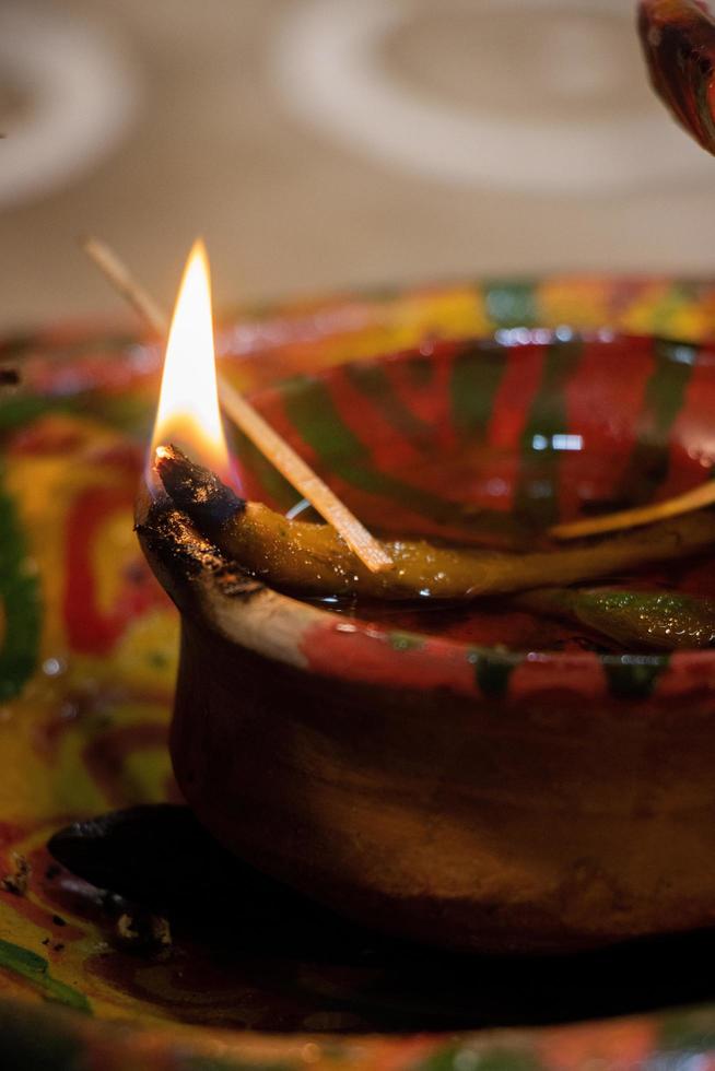 Hindu decorated clay lamp with fire on a blurry background. Hindu ritual and cultural Diya for special occasions. Decorated Hindu clay lamp. Traditional Hindu worship and puja elements close-up shot. photo