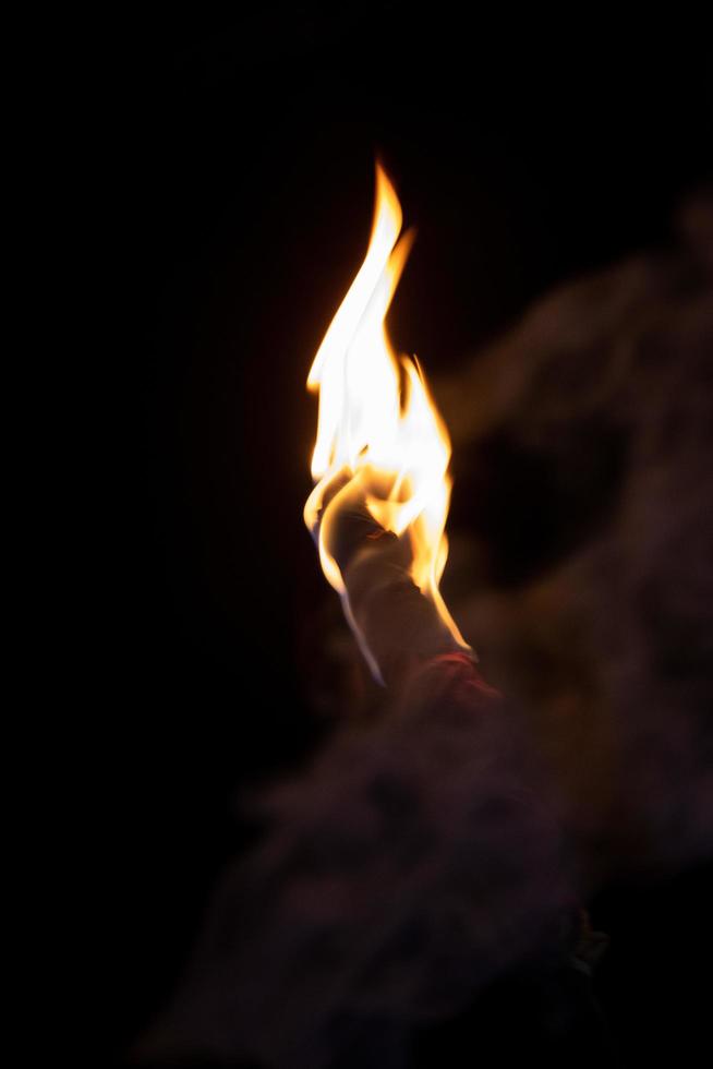 Fire torch on a dark background. A wooden torch with burning fire close-up shot. Torch with flame at night time. A wooden torch close-up view with bright yellow fire. Beautiful flame on a torch. photo