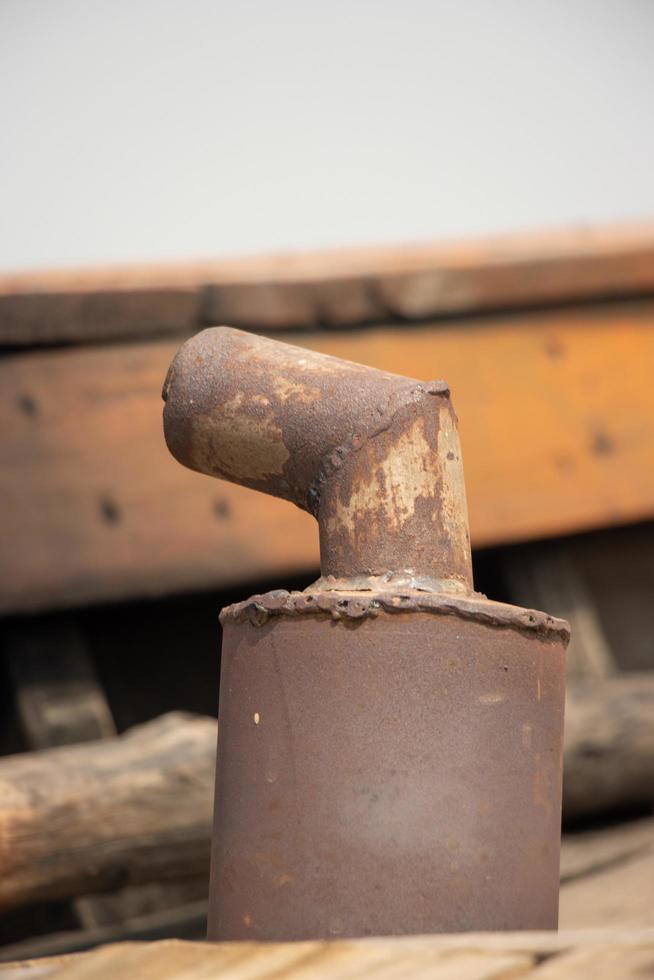 Ship exhaust pipe close-up shot on a blurry background. A Rusty exhaust pipe on a ship. Dirty smoke funnel on a wooden boat. Smoke chimney and exhaust pipe. Old and rusty smoke funnel on a ship. photo