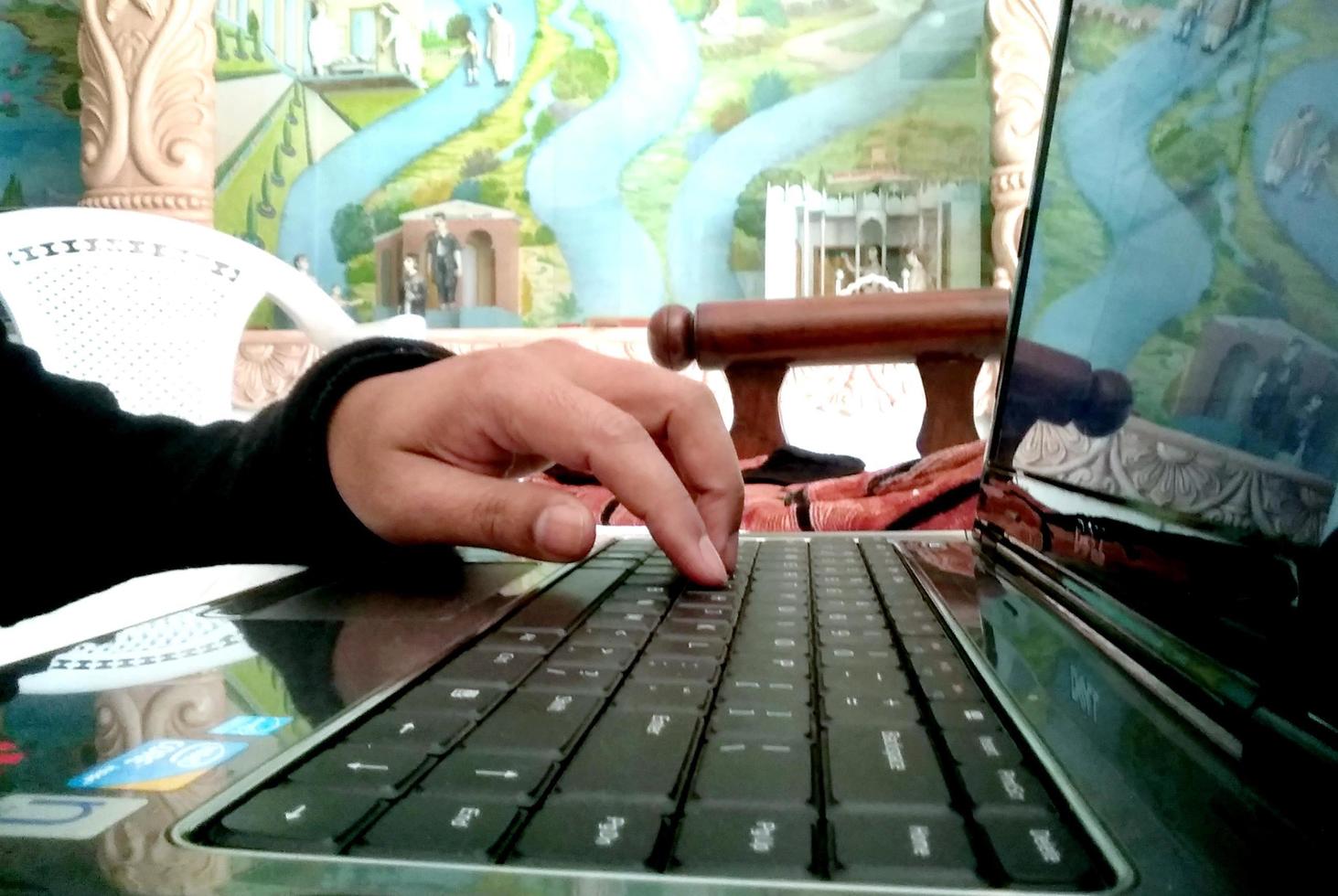 un masculino mano utilizar un ordenador portátil a hogar foto