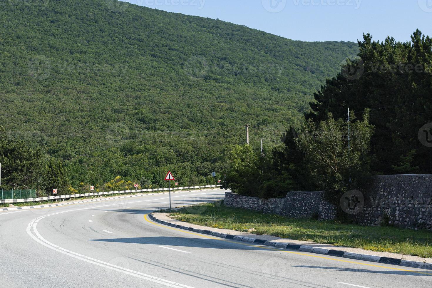 A steep mountain bend of a paved road. Auto travel. photo