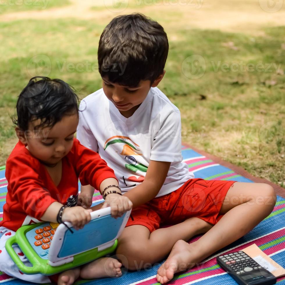 Two happy boys in society park, happy Asian brothers who are smiling happily together. Brothers play outdoors in summer, best friends. Toddler baby boy playing with his happy brother in the garden photo