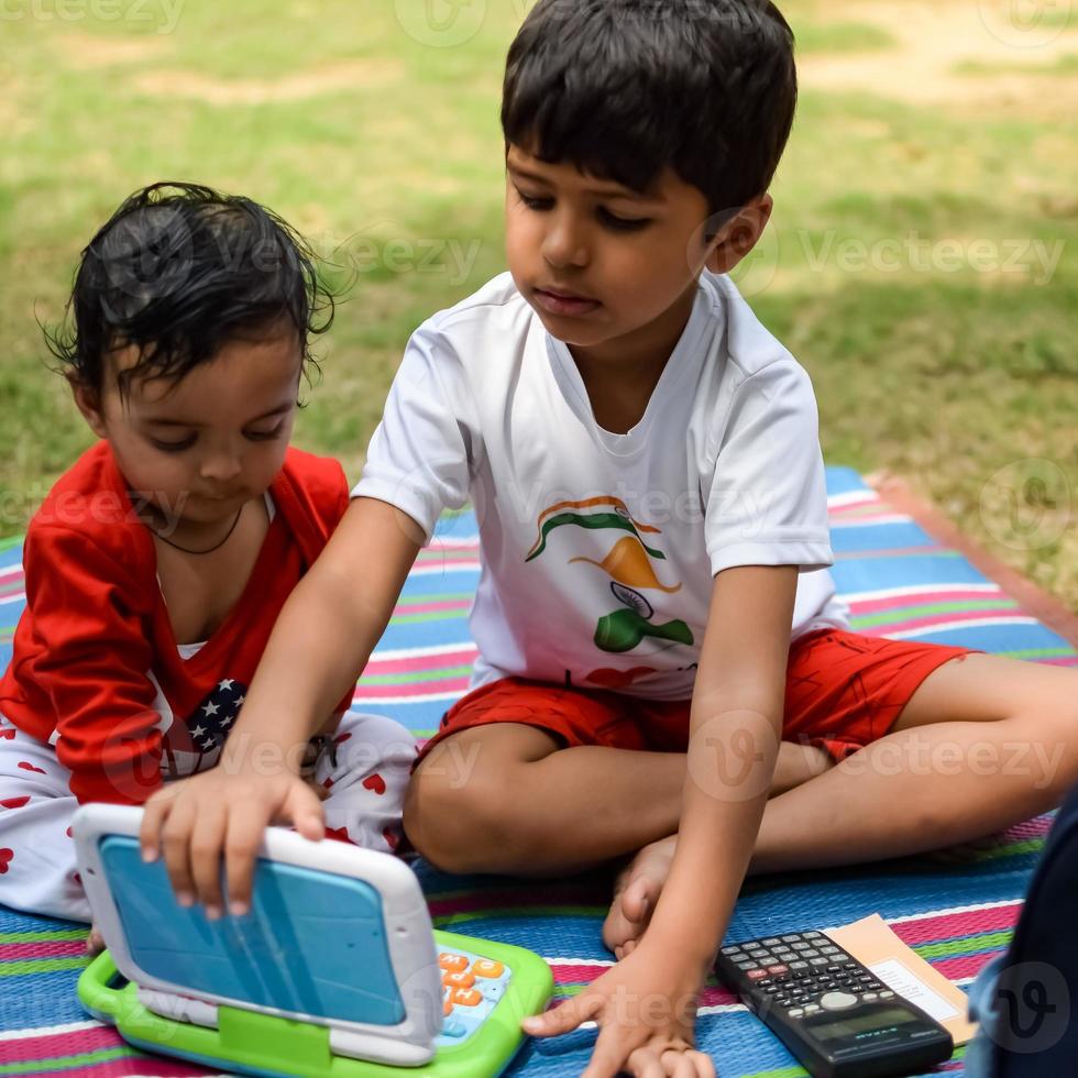 Two happy boys in society park, happy Asian brothers who are smiling happily together. Brothers play outdoors in summer, best friends. Toddler baby boy playing with his happy brother in the garden photo