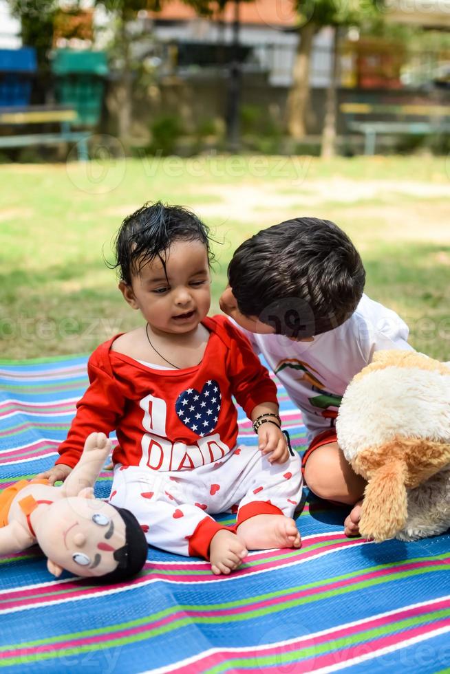 Two happy boys in society park, happy Asian brothers who are smiling happily together. Brothers play outdoors in summer, best friends. Toddler baby boy playing with his happy brother in the garden photo