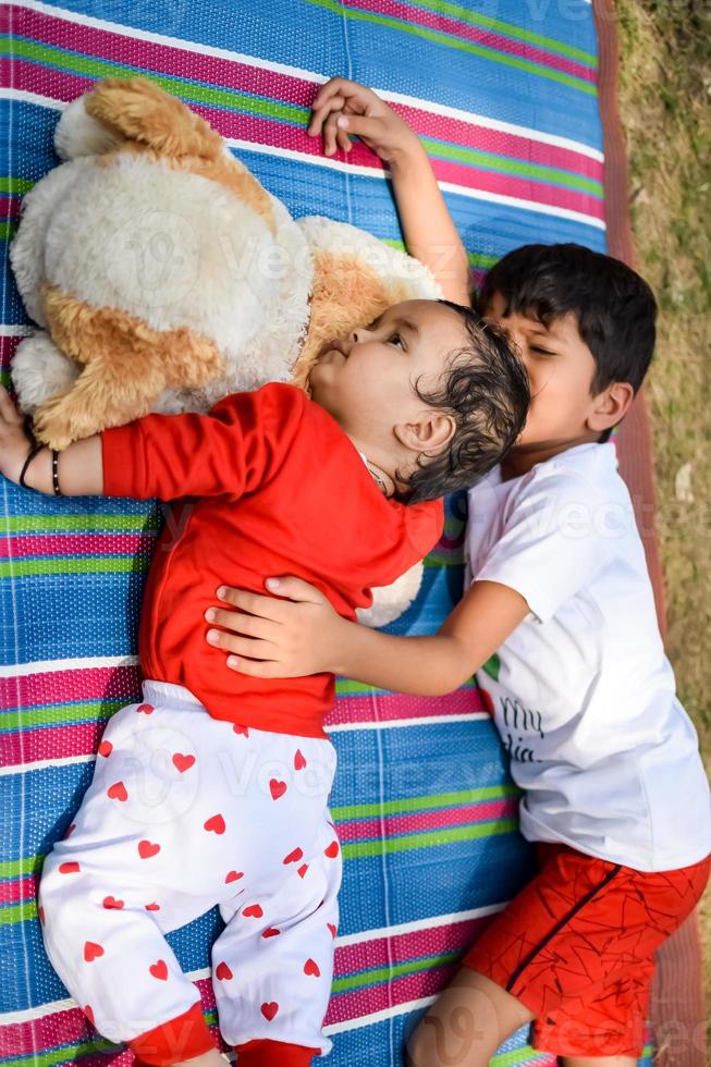 dos contento Niños en sociedad parque, contento asiático hermanos quien son sonriente felizmente juntos. hermanos jugar al aire libre en verano, mejor amigos. niñito bebé chico jugando con su contento hermano en el jardín foto