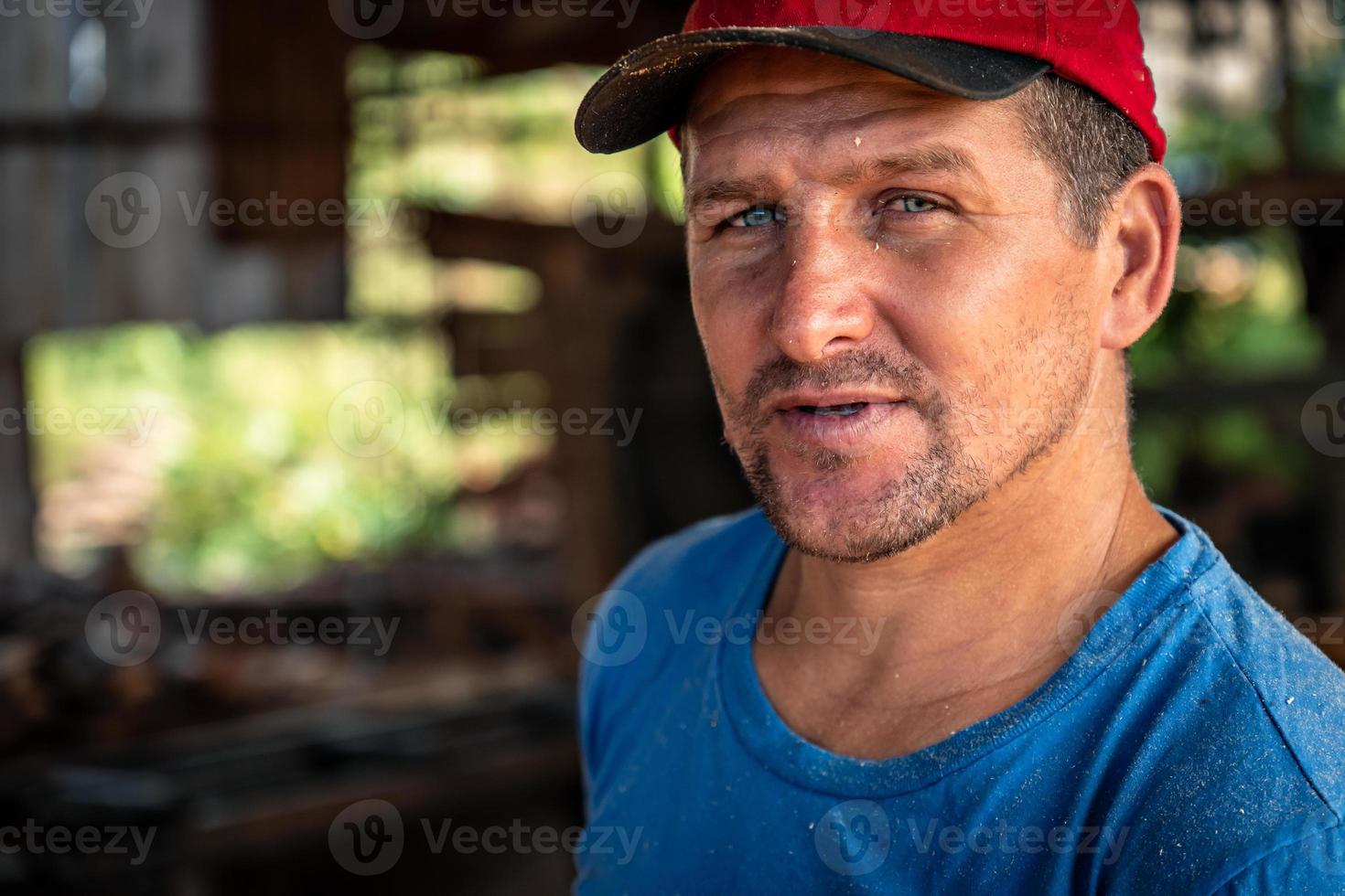 Close up portrait of a handsome male worker wearing a red hat looking at the camera. photo
