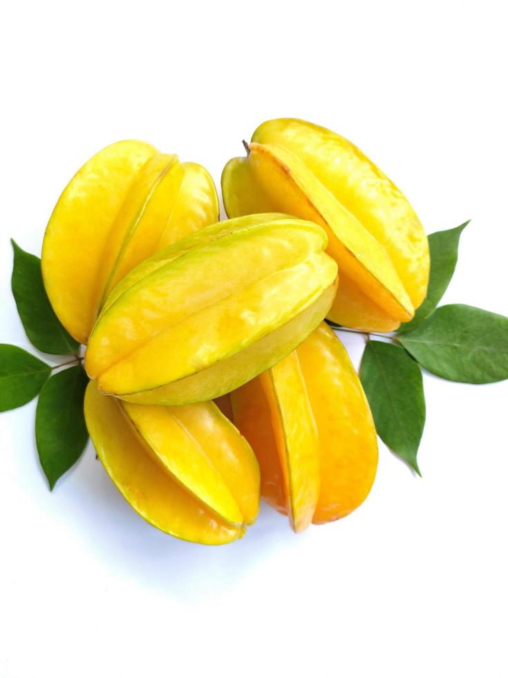 Carambola also known as star fruit, is the fruit of Averrhoa carambola, a species of tree native to tropical Southeast Asia. Star fruit with green leaves isolated on a white background photo