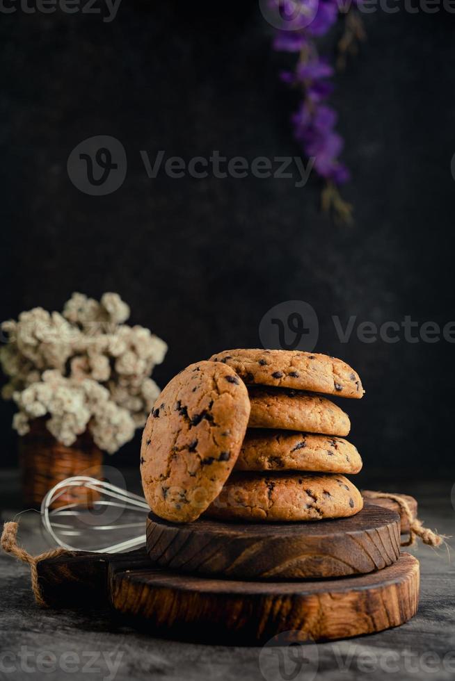 Homemade chocolate chip cookies on rustic wooden coaster and abstract background photo