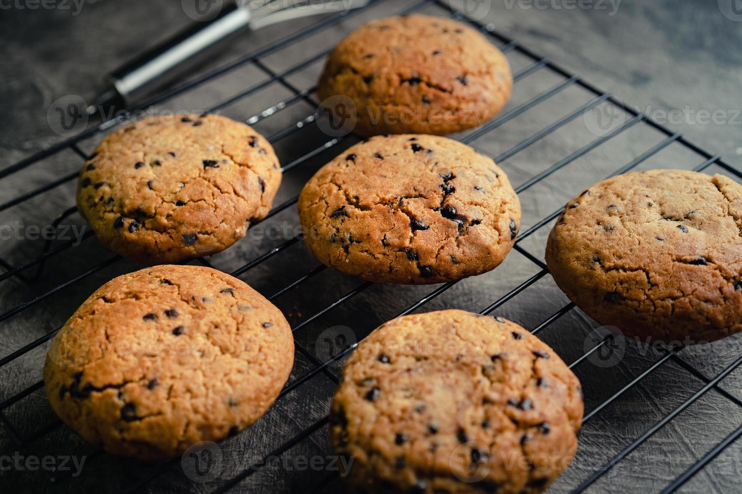 hecho en casa chocolate chip galletas en negro horneando enfriamiento bandeja y resumen antecedentes foto