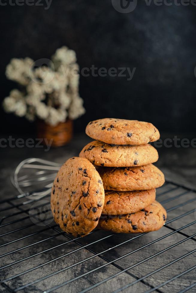 Homemade chocolate chip cookies on black baking cooling tray and abstract background photo