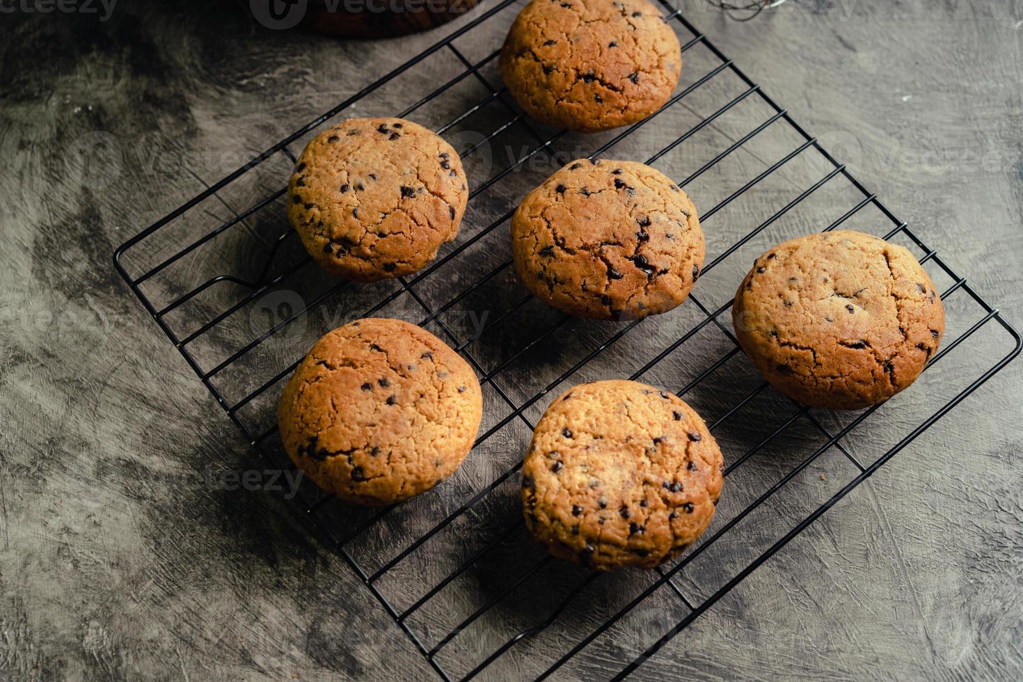 hecho en casa chocolate chip galletas en negro horneando enfriamiento bandeja y resumen antecedentes foto