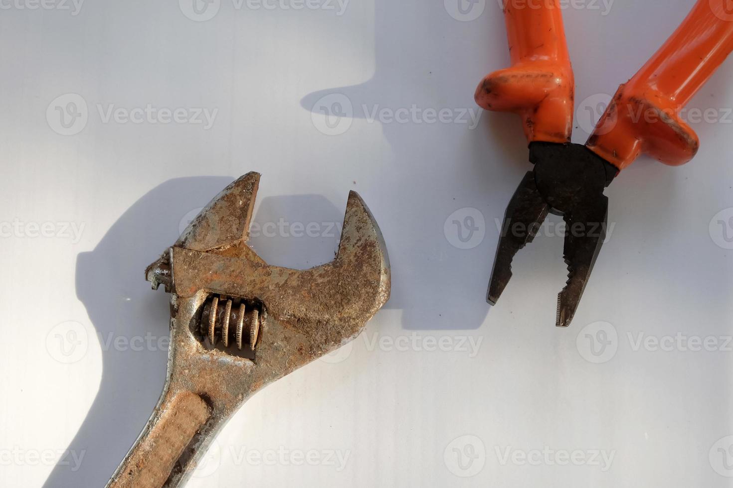 Old pliers and wrench with hard shadow on white background photo