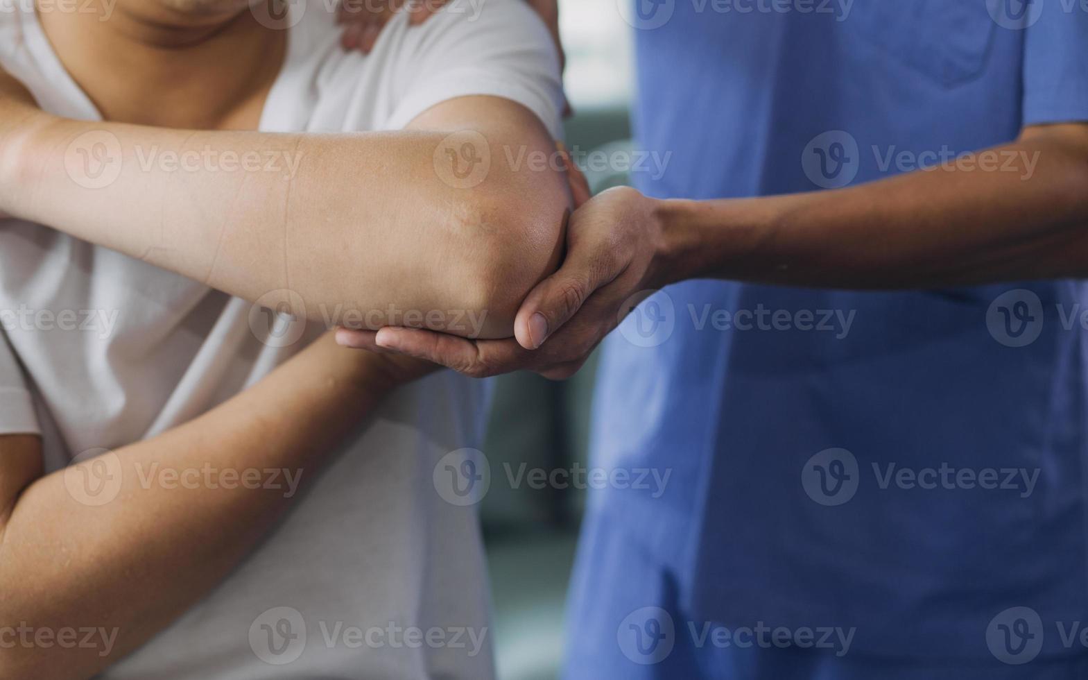 médico o fisioterapeuta trabajando examinando tratando lesionado brazo de atleta masculino paciente, extensión y ejercicio, haciendo el rehabilitación terapia dolor en clínica. foto