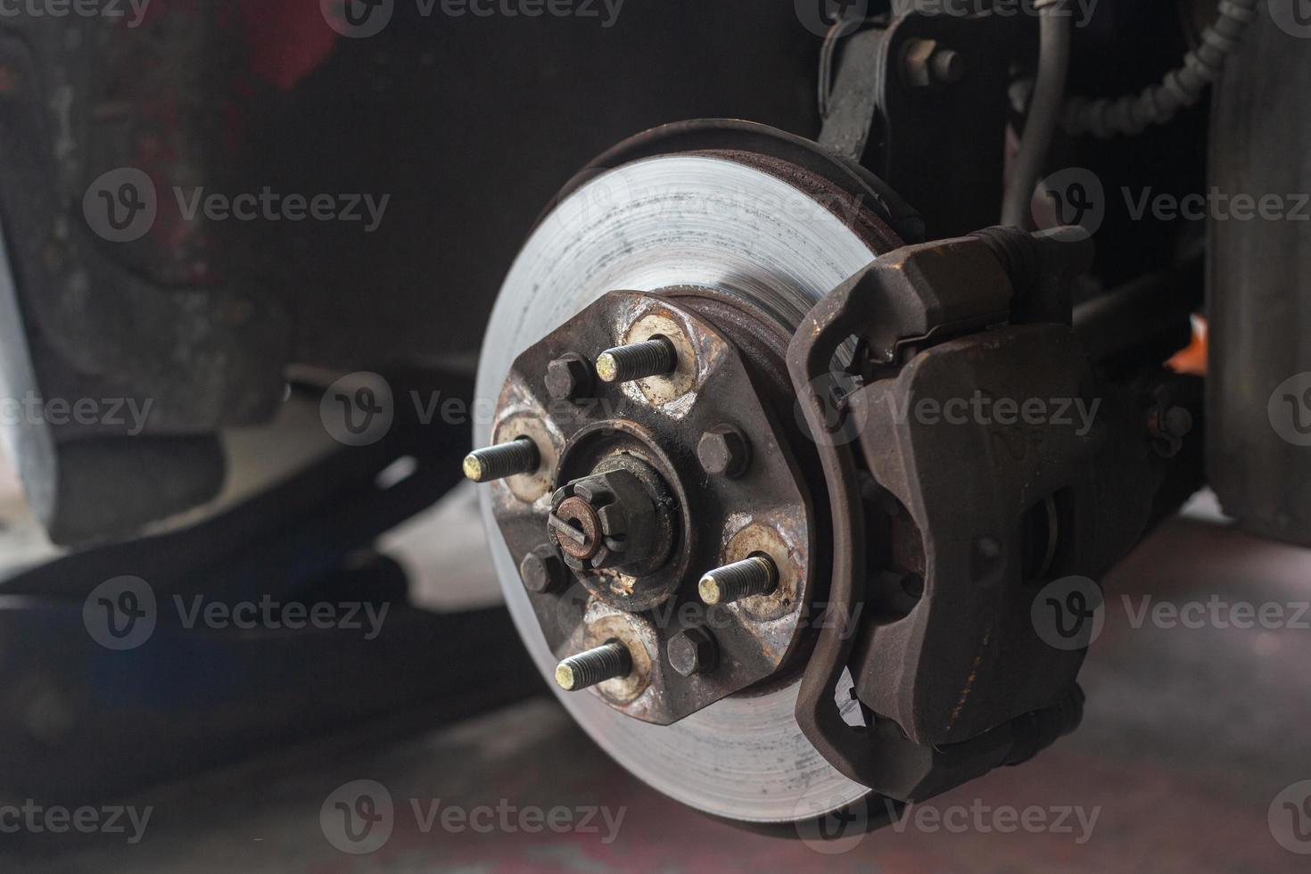 Brake discs, brake calipers and brake systems being maintained by a mechanic at a service center. Suspension of car for maintenance brakes and shock absorber systems.Close up. photo