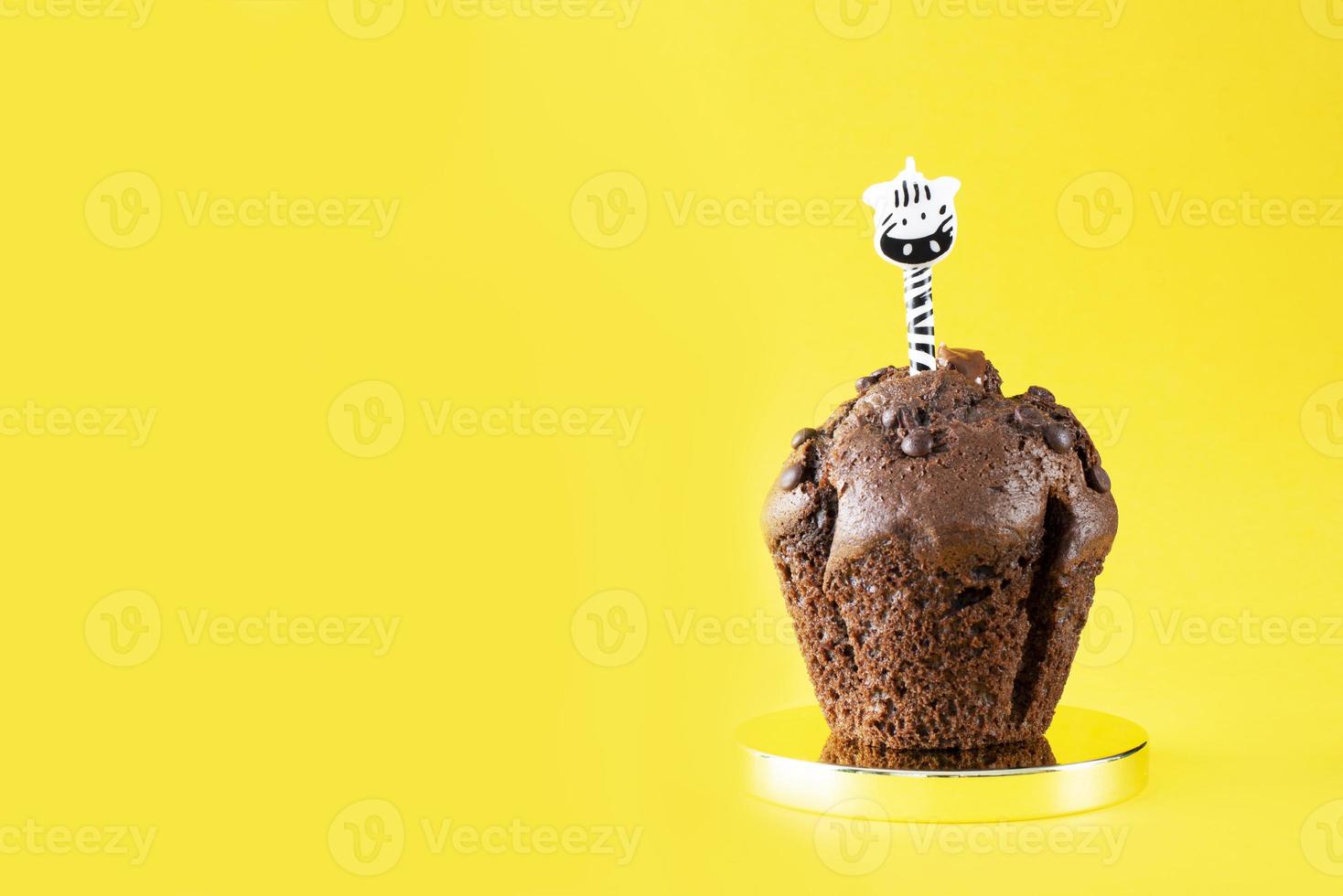 Chocolate cupcake with a candle on a yellow background. Cake. Chocolate candies. Bakery. Happy Birthday. photo