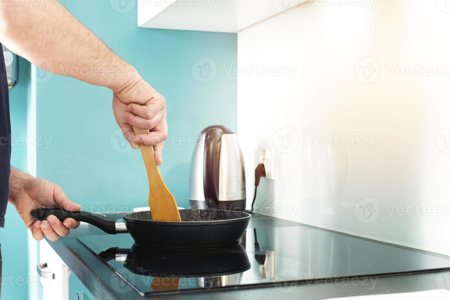 The man is cooking in the kitchen. Man's hands and frying pan. Frying. photo
