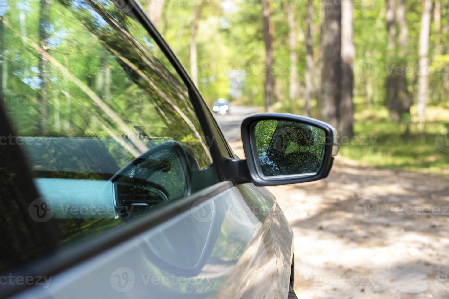 Gray car in the forest. Far-view mirror. Side mirror of the car. photo