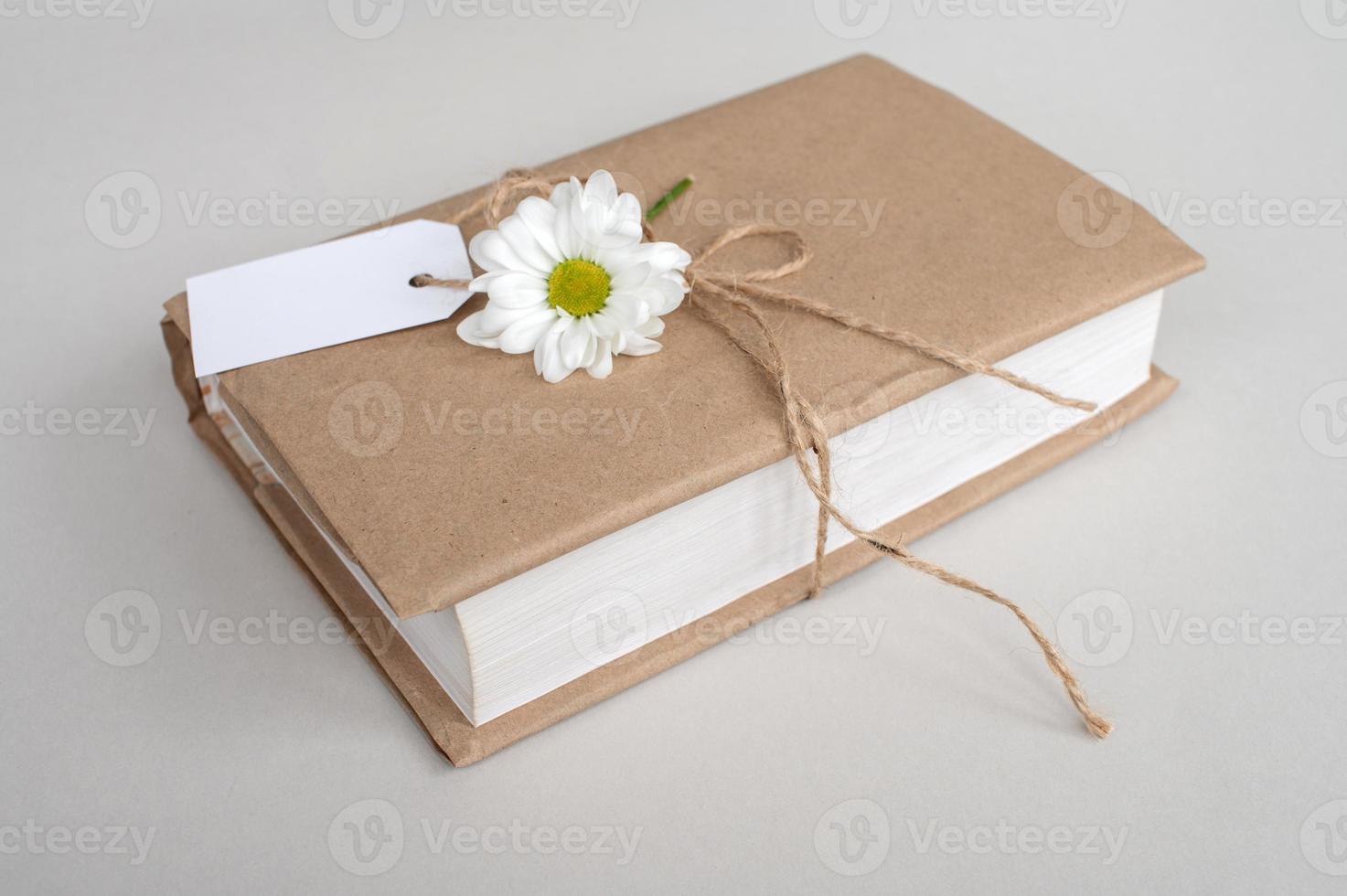 Kraft cover book with white tag, gift wrapping, top view, white label, decor with flower photo