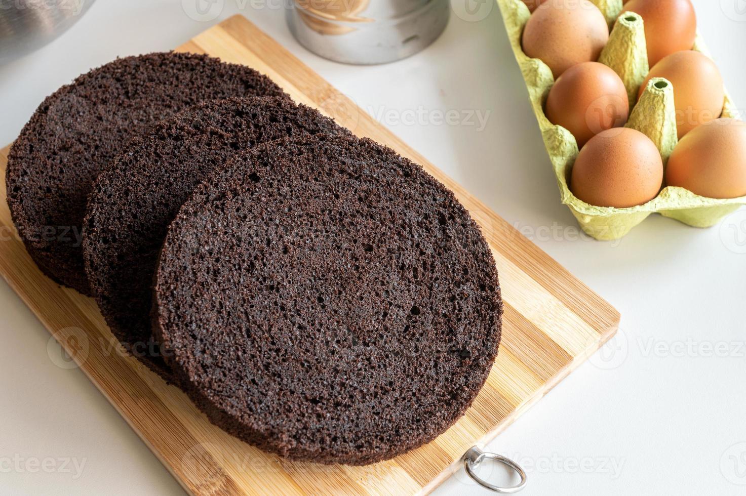 chocolate marrón galleta redondo pastel capas mentira en el cocina mesa, pollo huevos en el bandeja foto