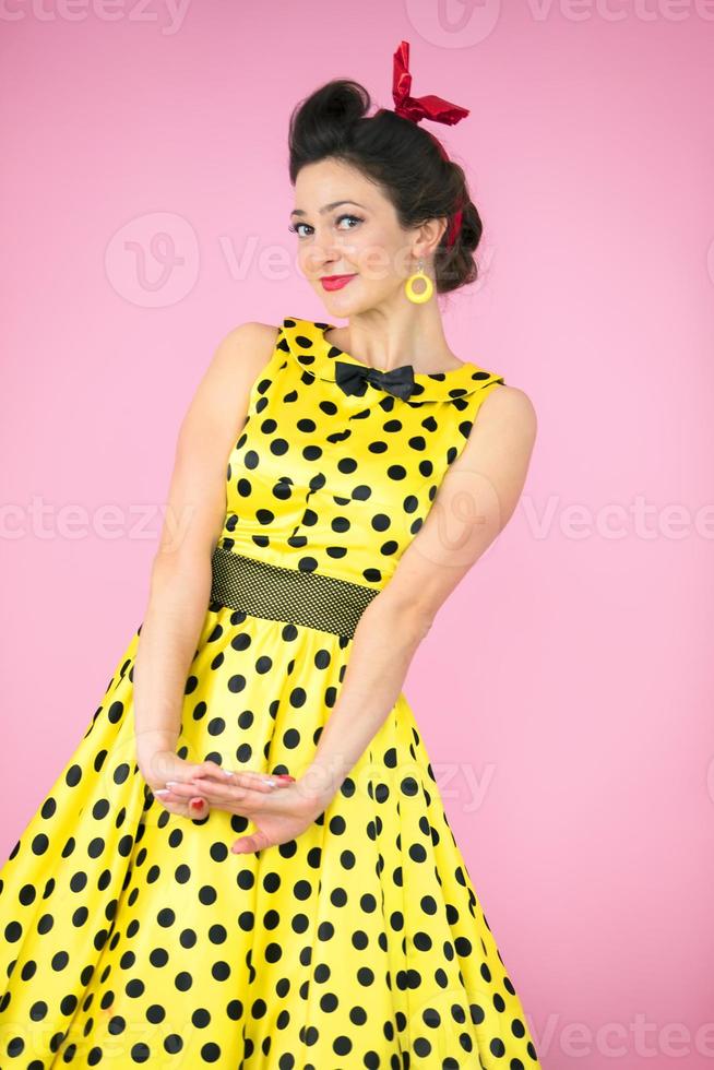 Retro girl. Beautiful woman in a dress with polka dots on a bright background. photo