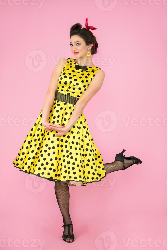 Retro girl. Beautiful woman in a dress with polka dots on heels on a bright background. photo