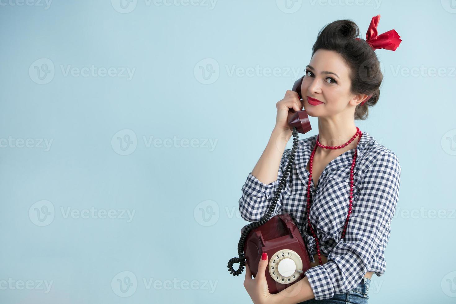 Woman in the style of the fifties. Beautiful retro woman with a dial phone. photo