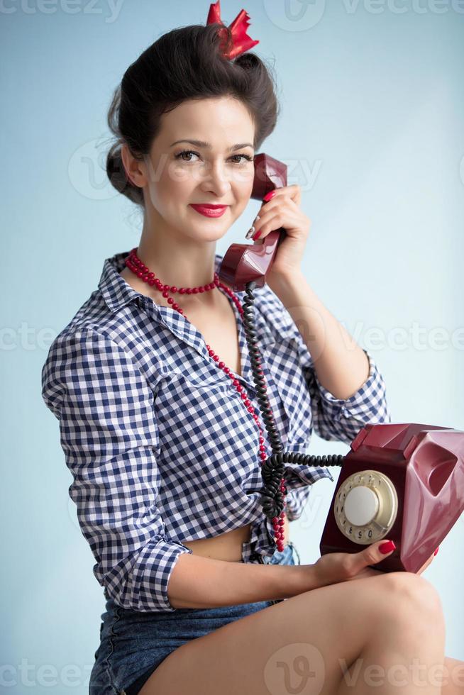 mujer en el estilo de el cincuenta retro mujer sostiene un teléfono. foto