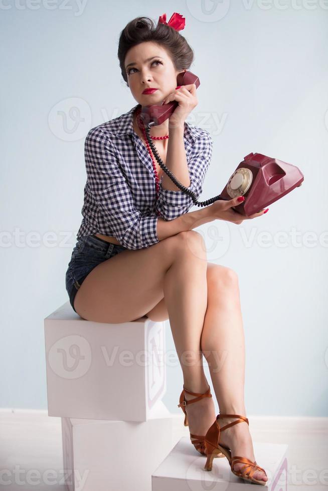 mujer en el estilo de el cincuenta hermosa retro niña con un retro teléfono en el estudio. foto