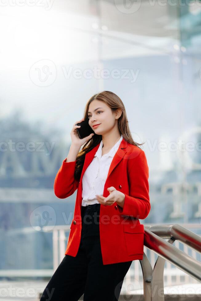 Beautiful female businesswoman use smartphone and holding laptop computer, Walk enjoy smiling while doing commuting at business center. photo