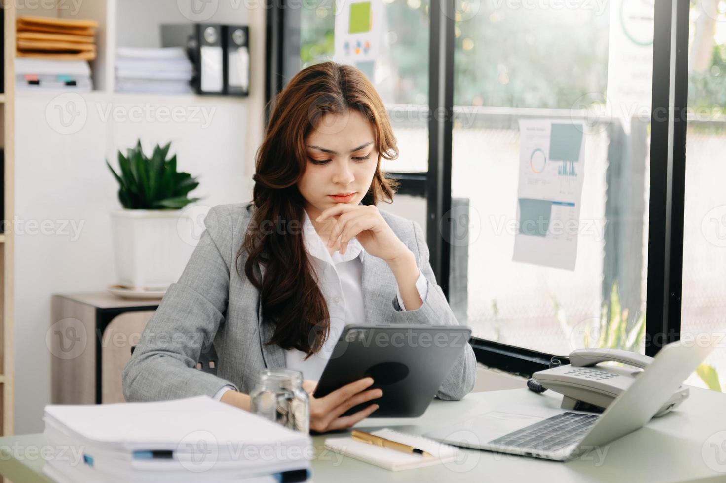 mujer que está cansada y pensando demasiado por trabajar con tableta y computadora portátil en la oficina moderna. foto