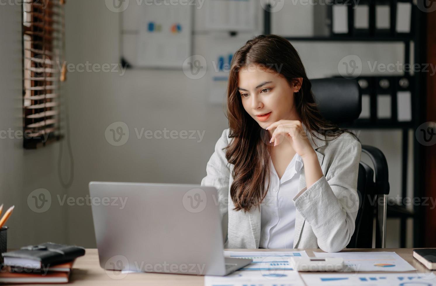 hermosa mujer de negocios asiática escribiendo una computadora portátil y una tableta colocadas en la mesa de la oficina foto