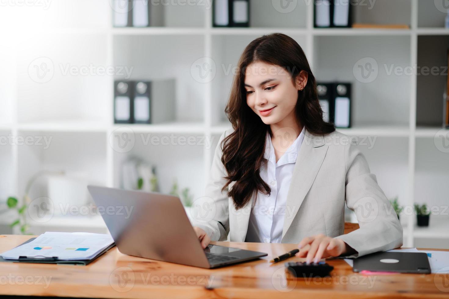 mujer de negocios o contador escribiendo a mano una computadora portátil trabajando para calcular en el escritorio el costo en la oficina en casa. foto