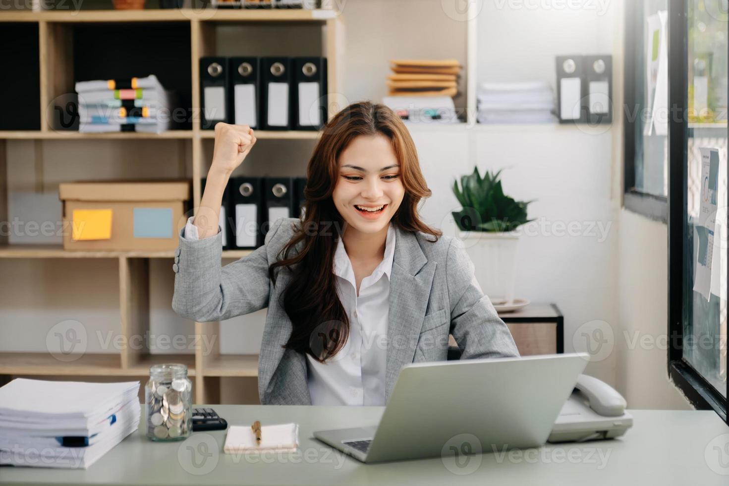 Asian business woman are delighted and happy with the work they do on their tablet, laptop and taking notes at the office. photo