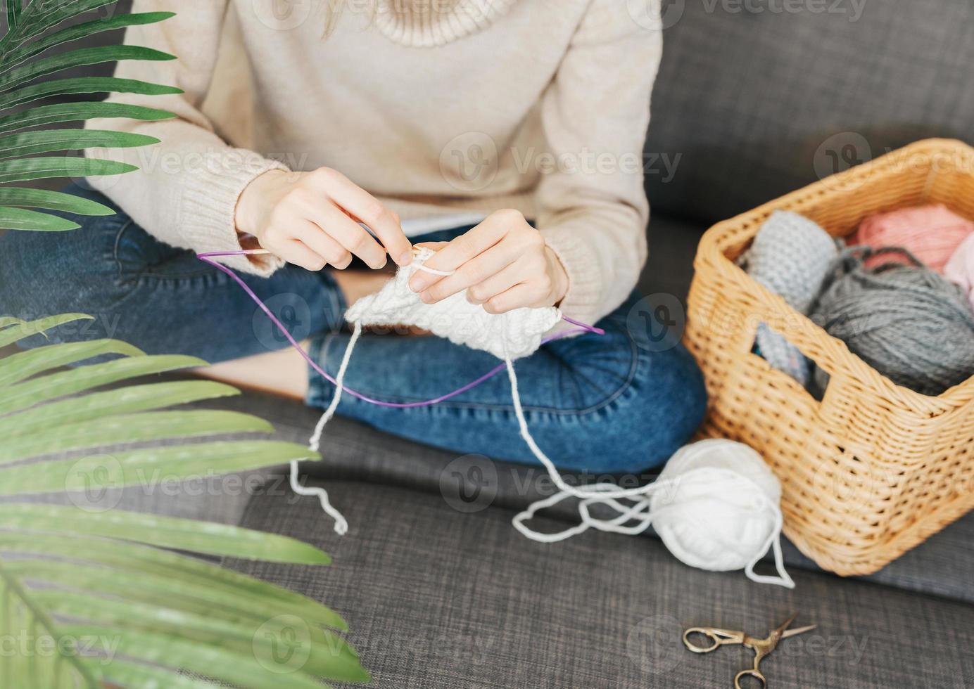 Young woman knitting warm scarf indoors photo