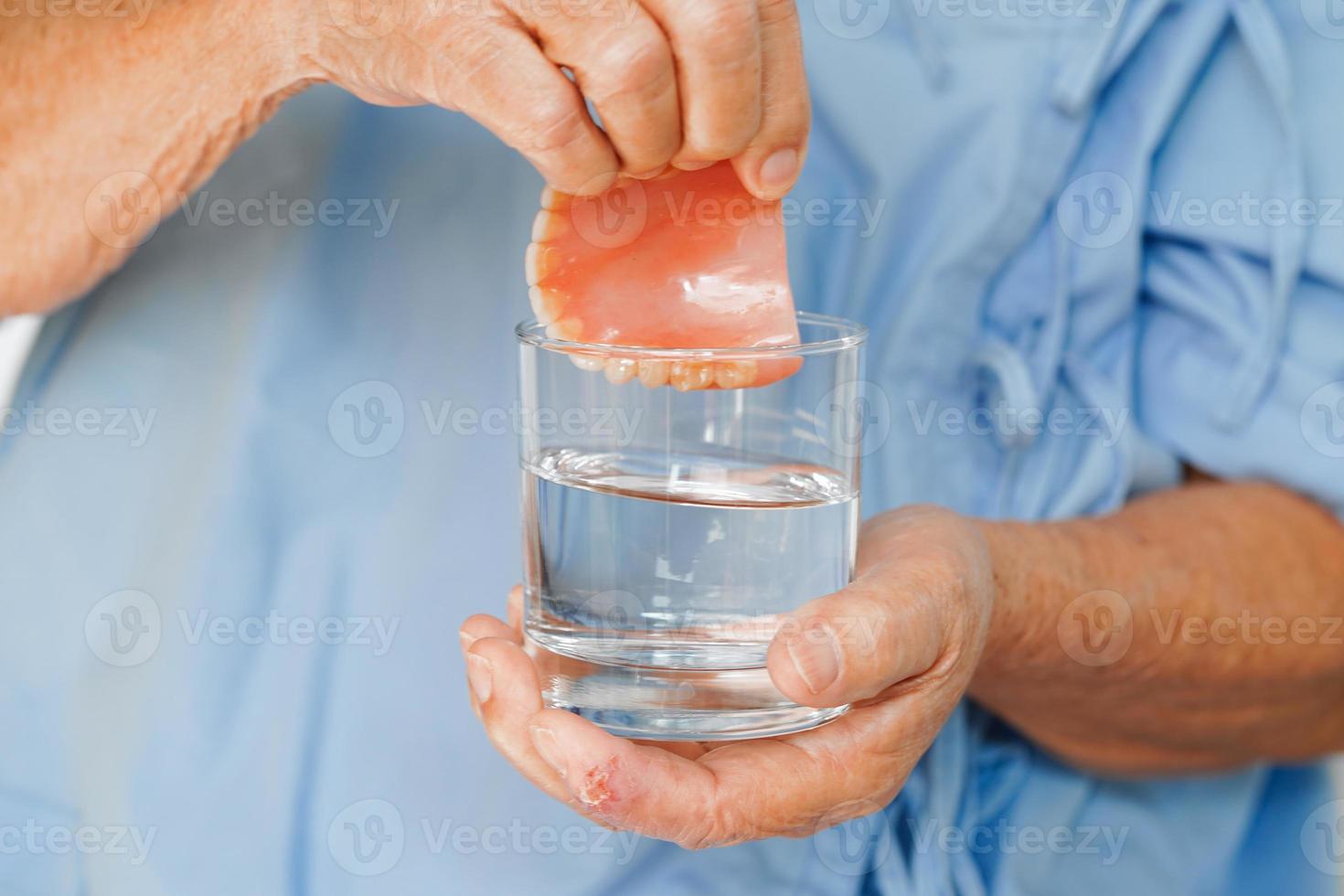 Asian senior woman patient holding teeth denture in her hand for chew food. photo